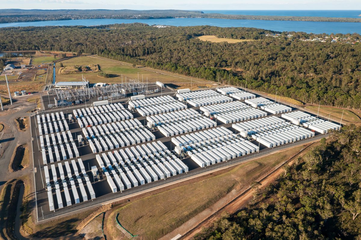 Aerial view of a large grid-scale battery storage facility beside a substation